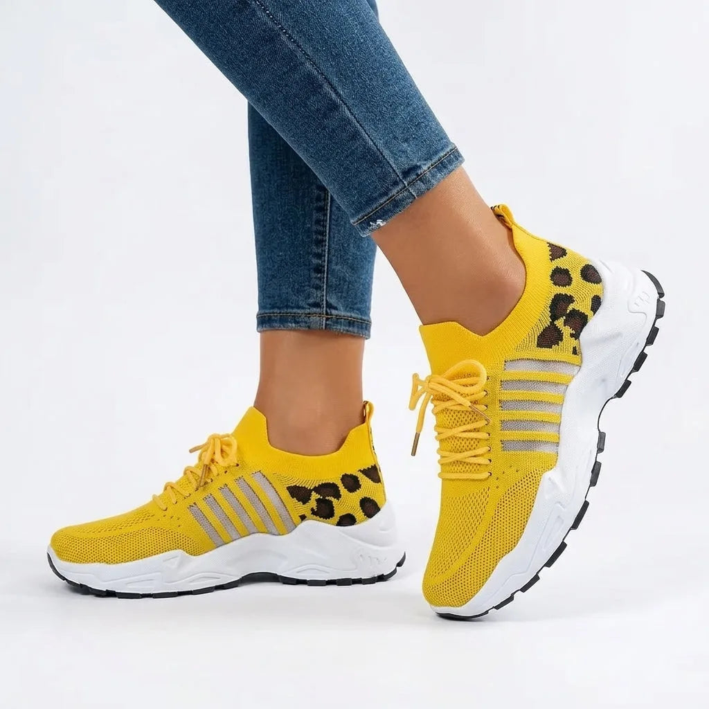Yellow knit trainer with leopard print panel and grey stripes worn on foot with jeans