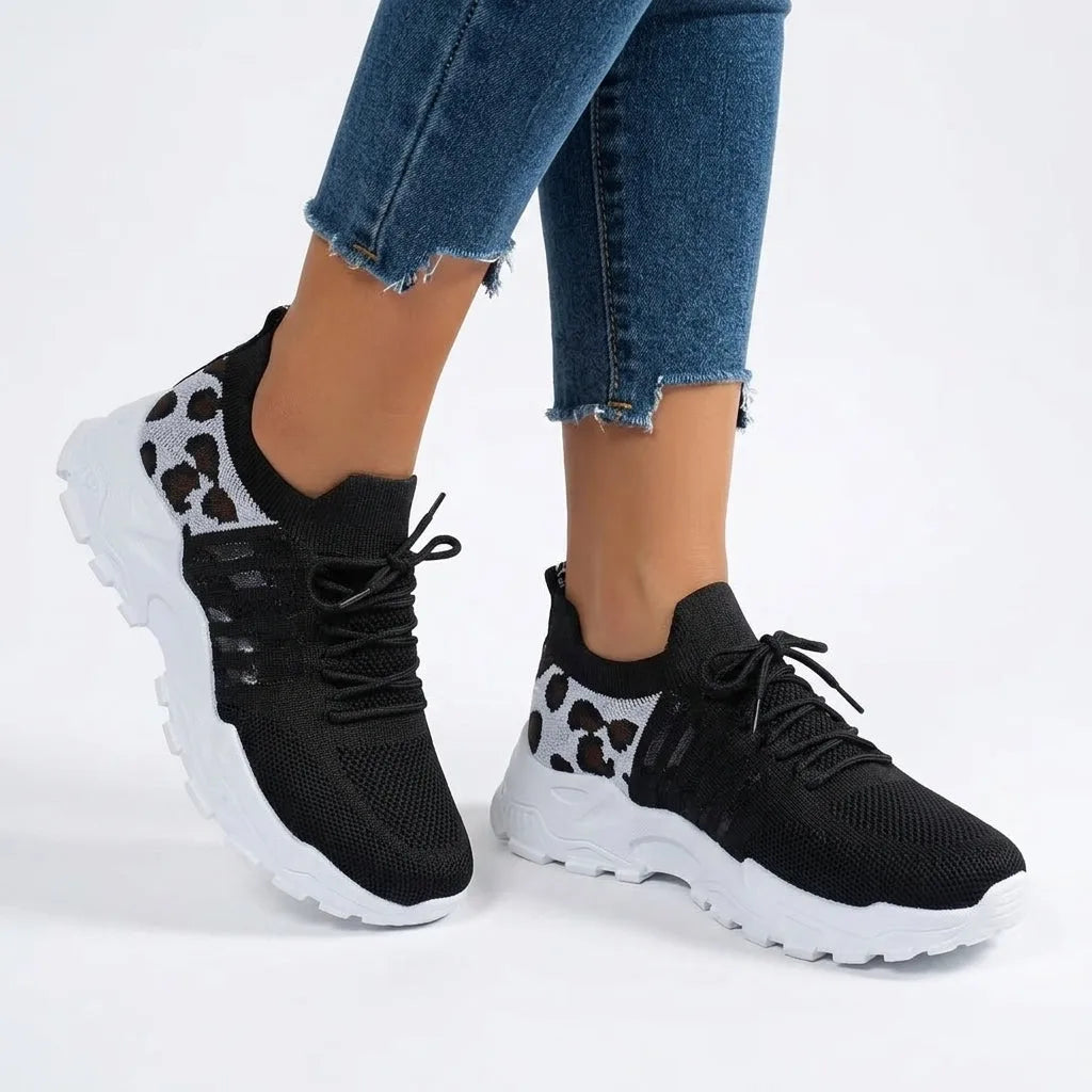 Black knit trainers with white leopard print panel and white chunky sole worn with jeans
