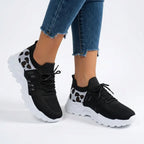 Black knit trainers with white leopard print panel and white chunky sole worn with jeans