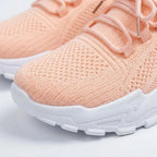 Close-up of peach knit trainer toe box and laces showing textured fabric and white sole detail