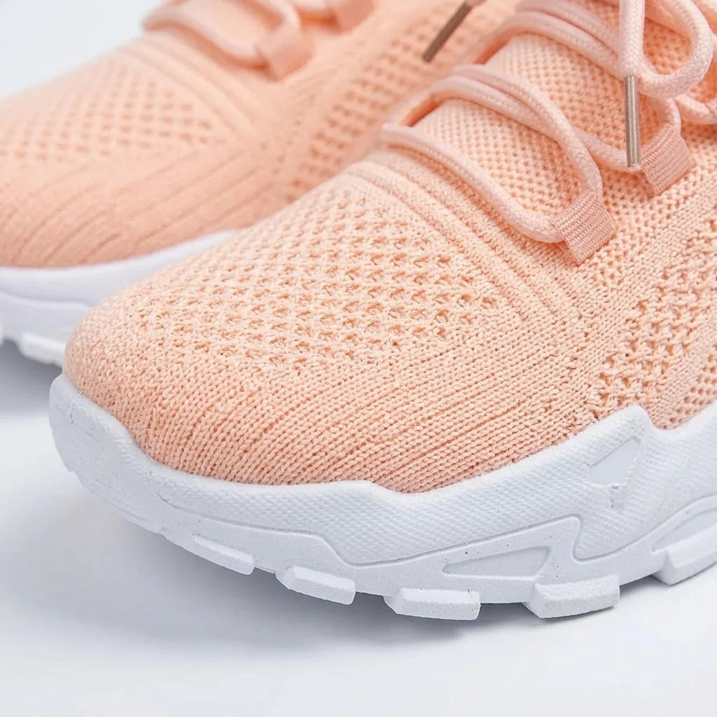 Close-up of peach knit trainer toe box and laces showing textured fabric and white sole detail