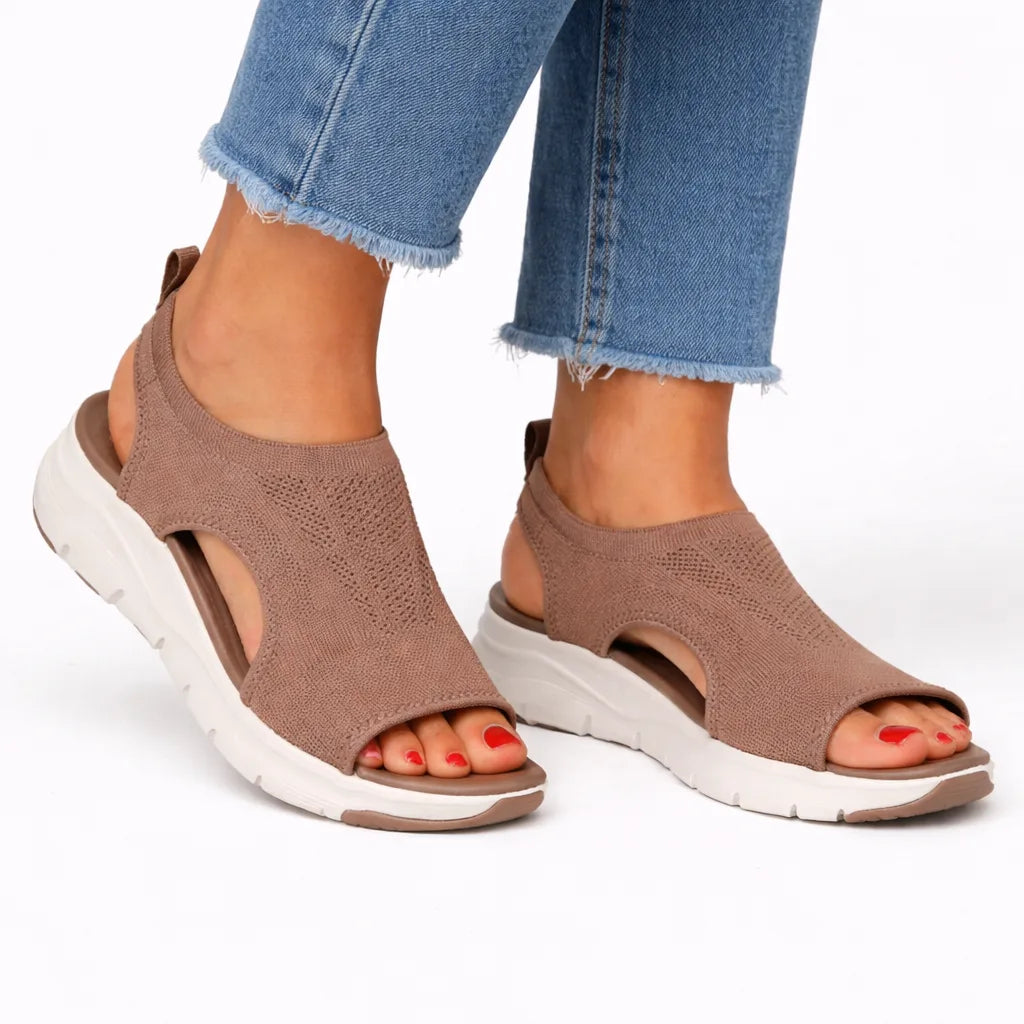 Brown knit sandal with white sole, cutout side panels and open toe, paired with denim.