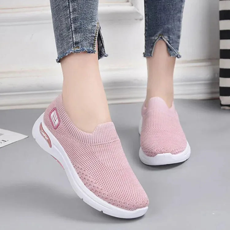 Model wearing pink knit slip-on trainers with cropped jeans, shown from the ankle down