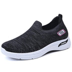 Side view of a black knit slip-on trainer with purple accent badge and white midsole