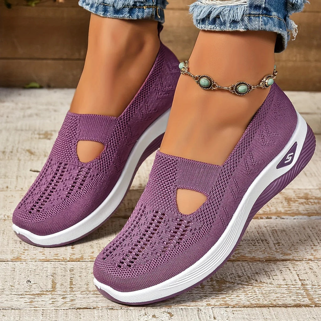 Close-up side view of purple woven knit slip-on trainers with cut-out detail and chunky white sole, worn with rolled denim jeans