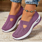Close-up side view of purple woven knit slip-on trainers with cut-out detail and chunky white sole, worn with rolled denim jeans