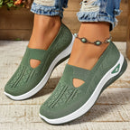 Olive green knit slip-on trainers with side cut-out and white ridged sole, shown from the front on model's feet