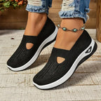 Black knit slip-on trainers with cut-out vamp detail and white platform sole, close side view on model wearing jeans