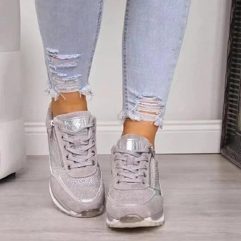 Grey diamante-covered trainer with silver accents and white sole seen from the front worn on foot