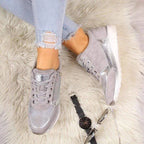 Grey and silver trainer with metallic heel tab and side zip, textured sole on wooden floor