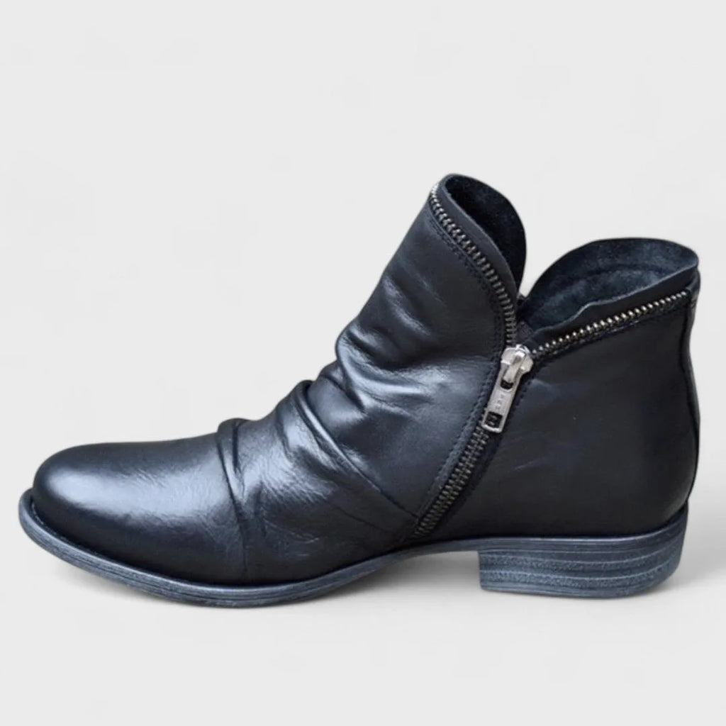 Black leather ankle boot shown from the side, ruched vamp and silver double-pull side zip