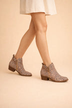 Leopard print suede ankle boots with gold-tone side zip, shown on model walking in a skirt