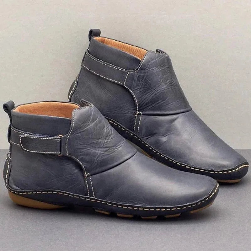 Green leather ankle boots with brown accent strap and stitched sole detail