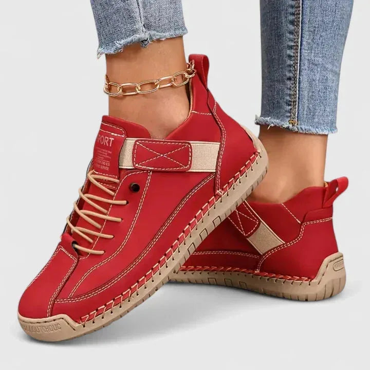 Red leather lace-up trainers with beige strap and hand-stitched trim, paired with cropped jeans