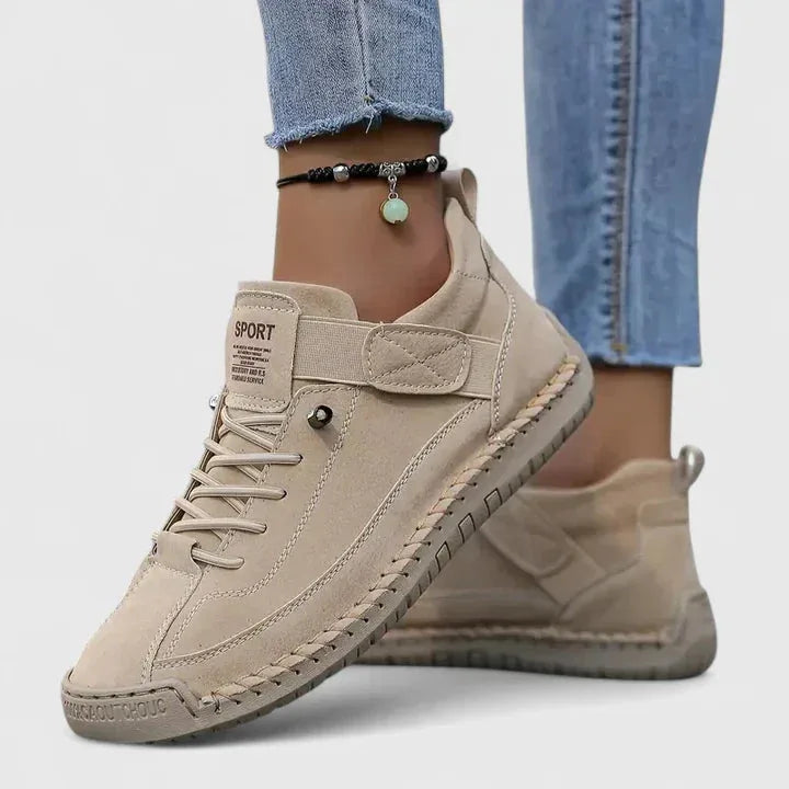 Beige suede lace-up trainers with tonal stitching and a textured rubber sole, worn with denim