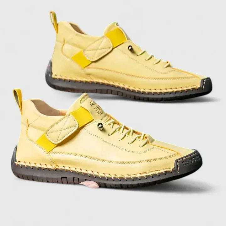 Pair of pale yellow leather trainers with quilted strap and brown sole, displayed side by side