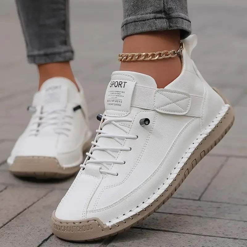 White leather trainer with contrast stitching and cream sole, worn with cropped grey jeans and a gold anklet