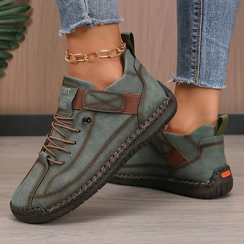 Sage green suede-look trainer with brown trim, elastic side strap and tan lug sole shown from side angle