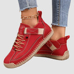 Red leather trainer paired with tan laces and elastic strap, shown against a plain grey studio background