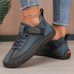 Denim blue leather trainer with orange sole accent and contrast stitching, styled with light wash jeans