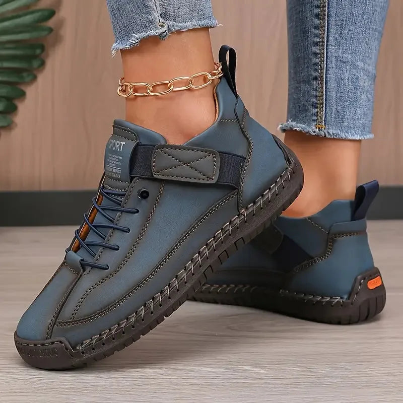 Denim blue leather trainer with orange sole accent and contrast stitching, styled with light wash jeans