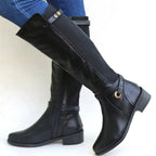 Side view of a black knee-high leather boot with elastic gusset panel and buckle detail, worn with jeans