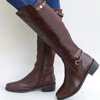 Side view of a brown knee-high leather boot showing the stretch calf panel and gold-tone ring hardware