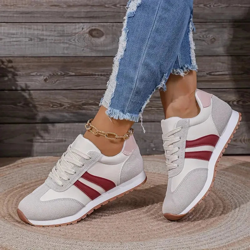 Side view of grey trainers featuring burgundy side stripes and a pale pink heel tab, styled with frayed denim.