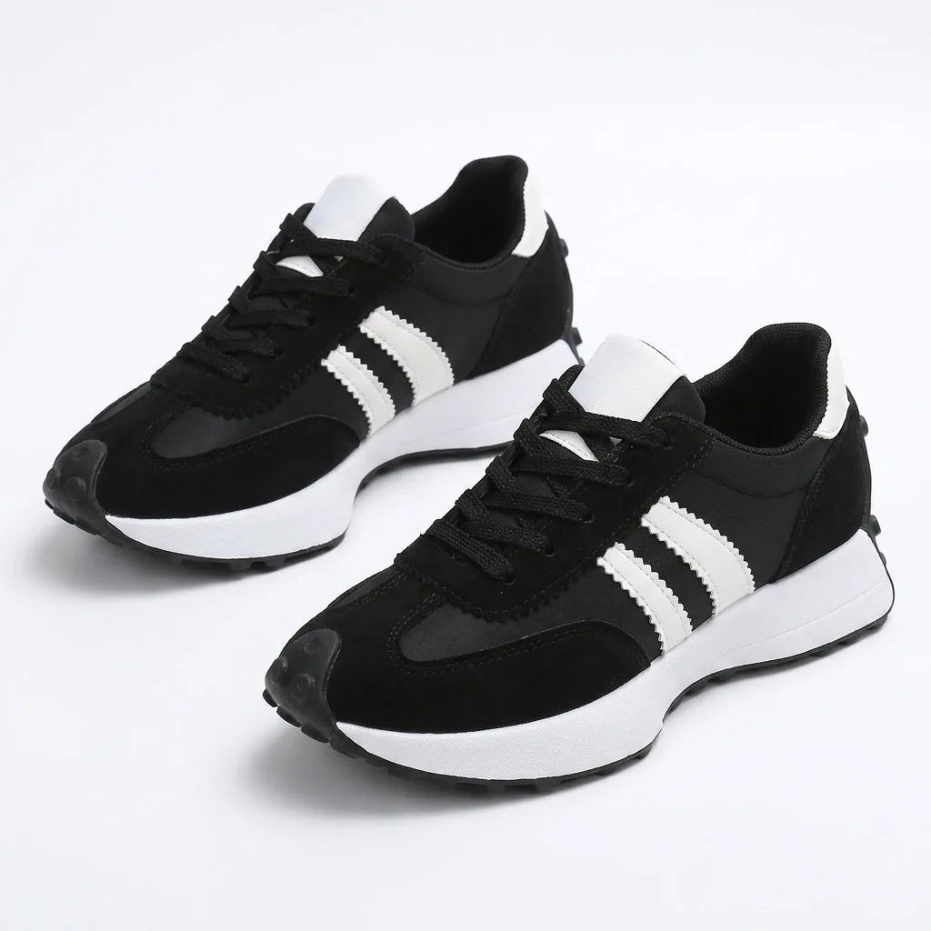 Pair of black retro trainers with white side stripes and white heel tab, shown together on a plain background