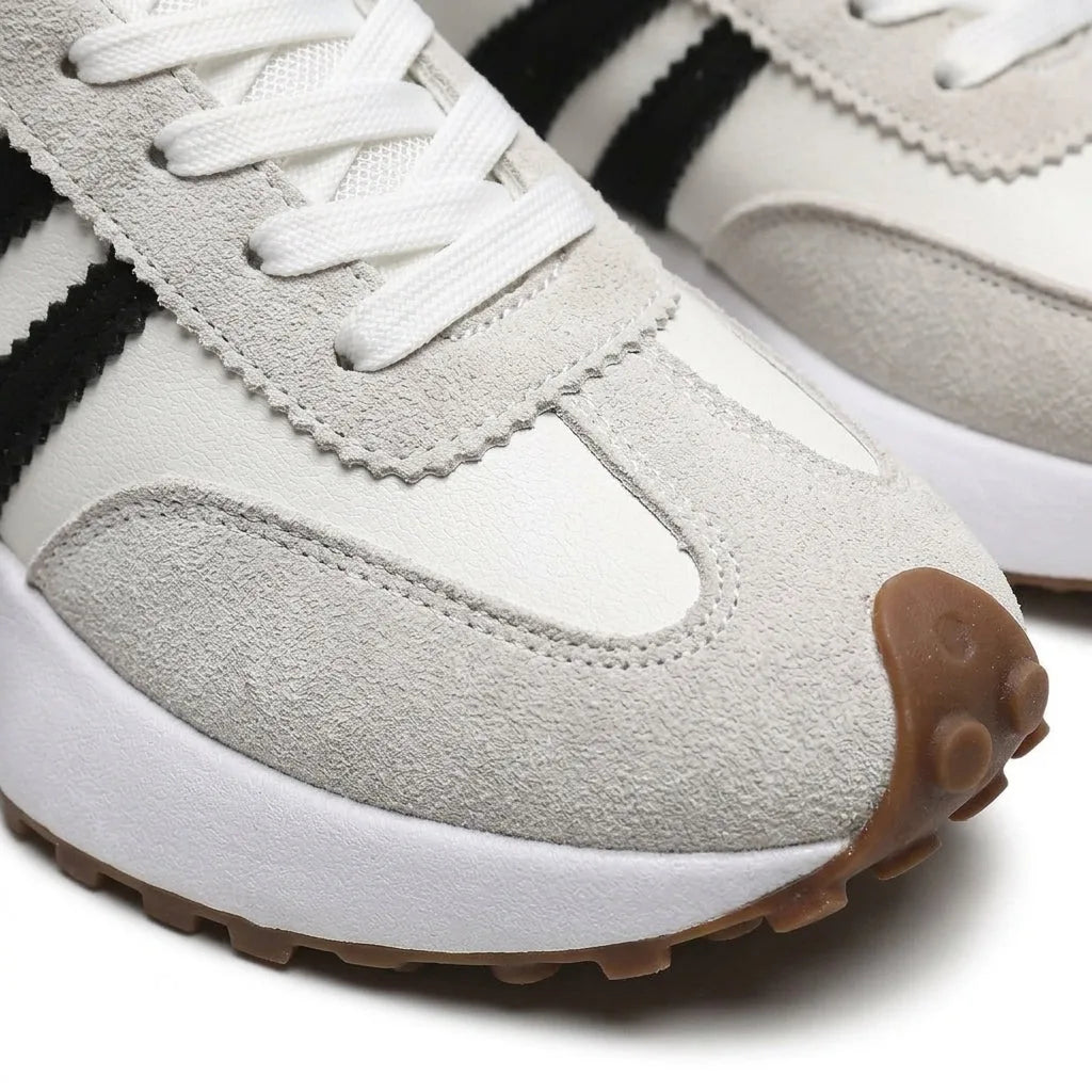 Close-up of the white trainer's textured toe cap, suede panels and black stripe stitching detail