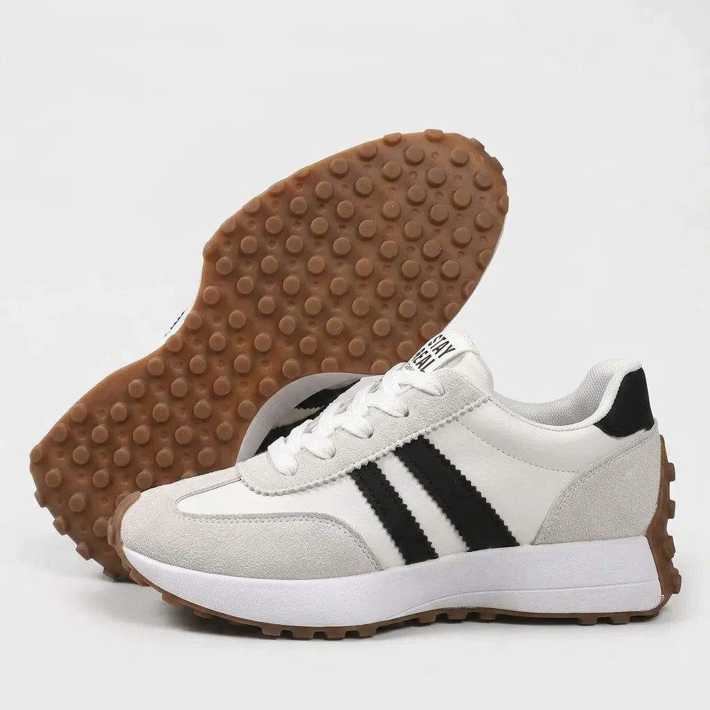 White trainer shown on its side next to its sole, revealing the chunky gum-coloured tread pattern