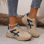 Side-by-side view of beige and navy colour-block trainers with lace-up front and ridged gum sole, worn with jeans