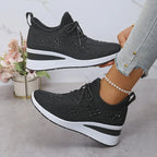 Side view of black knit trainers with rhinestone star pattern, lace-up front and white wedge sole