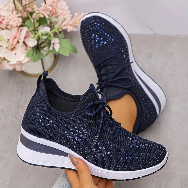 Sole view showing textured tread of black rhinestone-embellished knit trainers paired with a wedge midsole