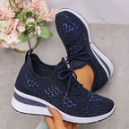 Sole view showing textured tread of black rhinestone-embellished knit trainers paired with a wedge midsole