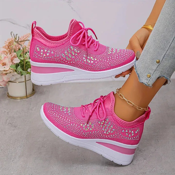 Light blue knit trainers with silver rhinestone detailing, side profile showing white wedge sole