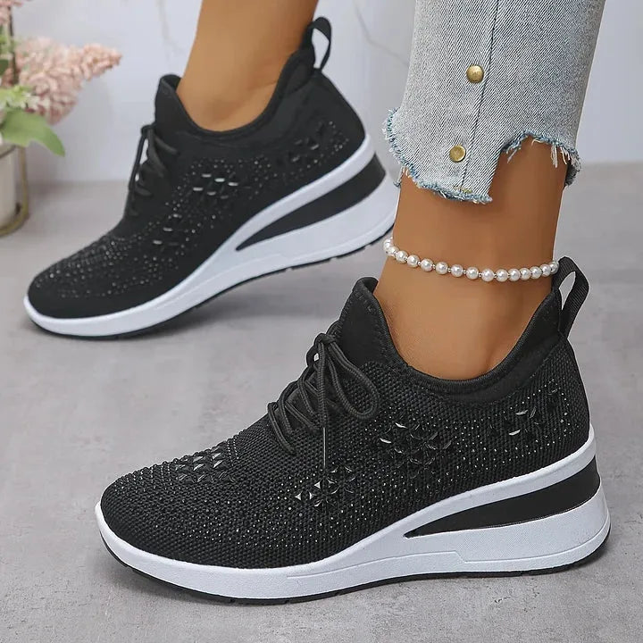 Close-up side view of white knit trainers with silver sparkle detailing and textured white sole