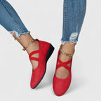 Red suede ballet flats with crossed ankle straps, worn with rolled-up denim jeans, top view