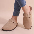 Taupe suede clog slippers worn with cropped jeans, side view highlighting adjustable buckle strap