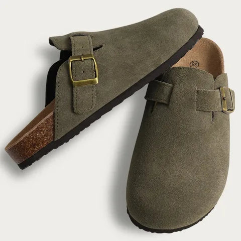 Pair of olive green suede clog slippers shown from above and side, displaying buckle and cork footbed