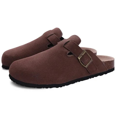 Pair of brown suede clog slippers angled to show buckle strap and ridged black outsole
