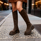 Close-up of brown suede knee-high boots with visible topstitching and side zip detail
