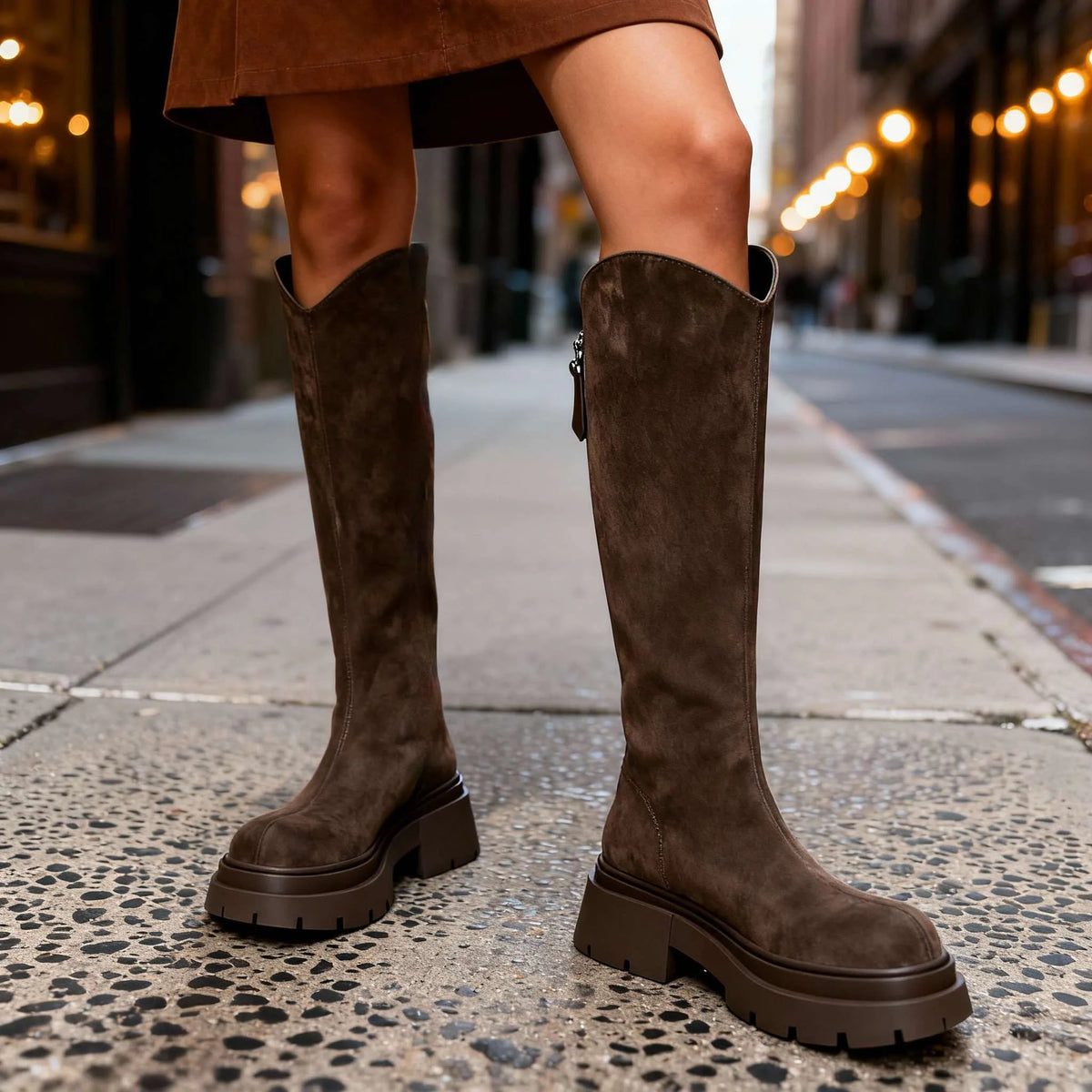 Front-facing view of brown suede knee-high boots showing rounded toe and stacked block heel