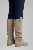 Back view of beige suede knee-high boots showing pull tab, side zip and buckle ankle strap