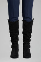 Front view of the boots shown in a khaki green suede tone with pull tab and buckle strap detail
