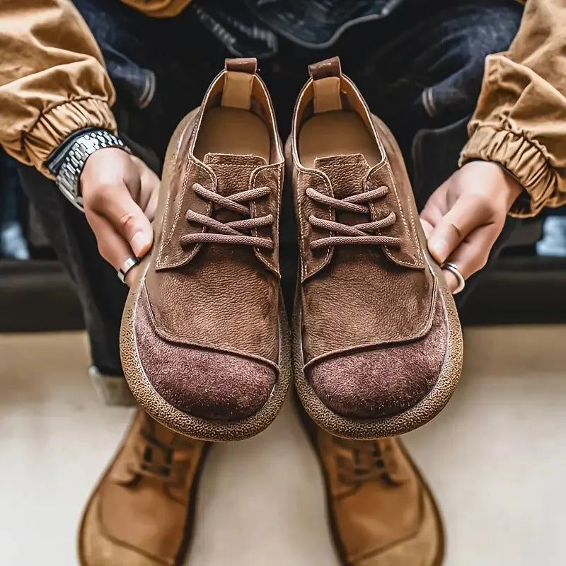 Close-up top-down view of tan suede lace-up shoes on a white surface beside a second pair in burgundy suede