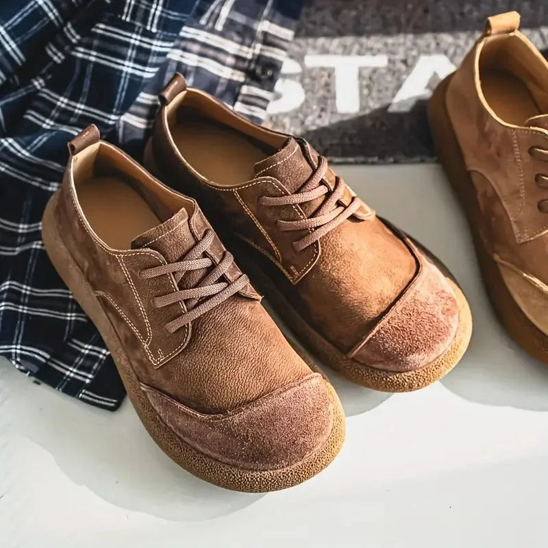 Close-up of the toe area of a tan suede shoe showing the layered suede panel stitched onto smooth leather