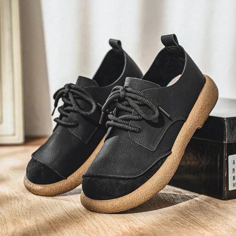Pair of tan suede derby shoes viewed from above resting on a light wood surface