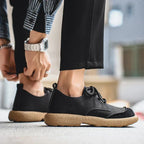Close-up of a dark brown suede shoe's rounded toe and stitched suede overlay detail