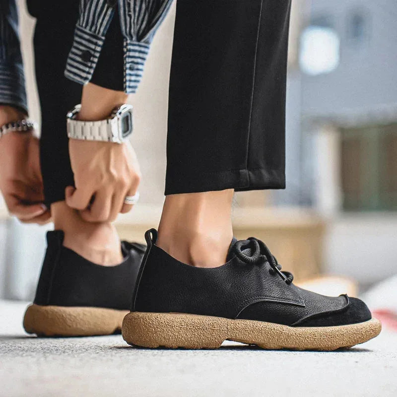 Close-up of a dark brown suede shoe's rounded toe and stitched suede overlay detail